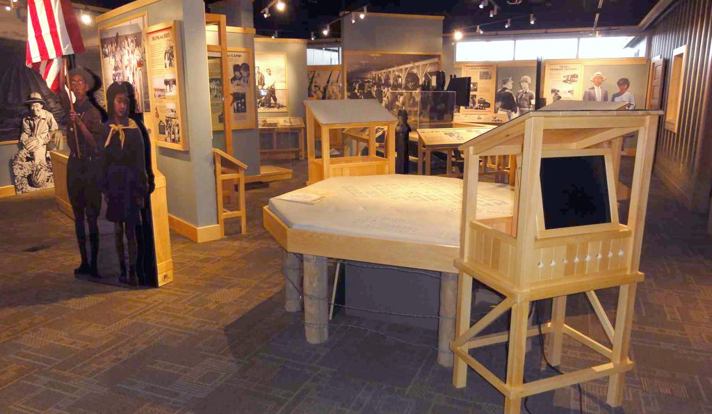 A scale model of the camp is flanked by "guard towers" holding interactive screens. Other displays in this area explore daily life for detainees at Heart Mountain.