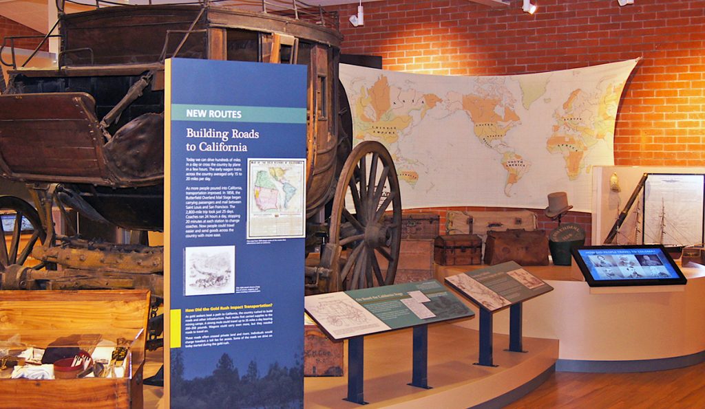 A stagecoach and artifacts anchor this display about transportation to California. Visitors can explore an interactive map to see how waves of gold seekers converged from across the world. 